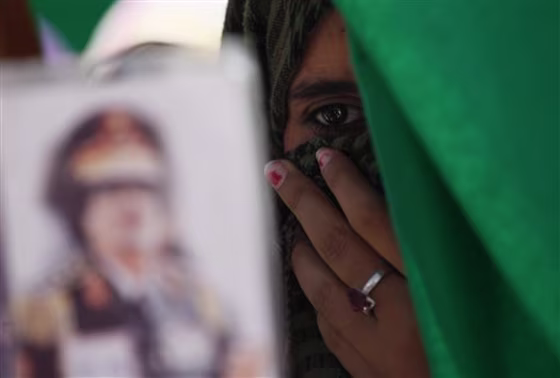 In this photo taken on a government-organized tourm a Libyan student holds a portrait of Libyan leader Moammar Gadhafi, outside the damaged university building in Tripoli, Libya, on Saturday.